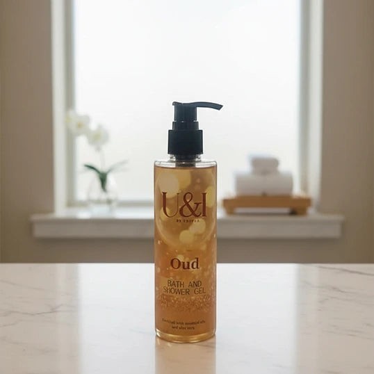 U&I Oud Bath & Shower Gel in a 200ml clear pump bottle with golden liquid, displayed on a marble surface.