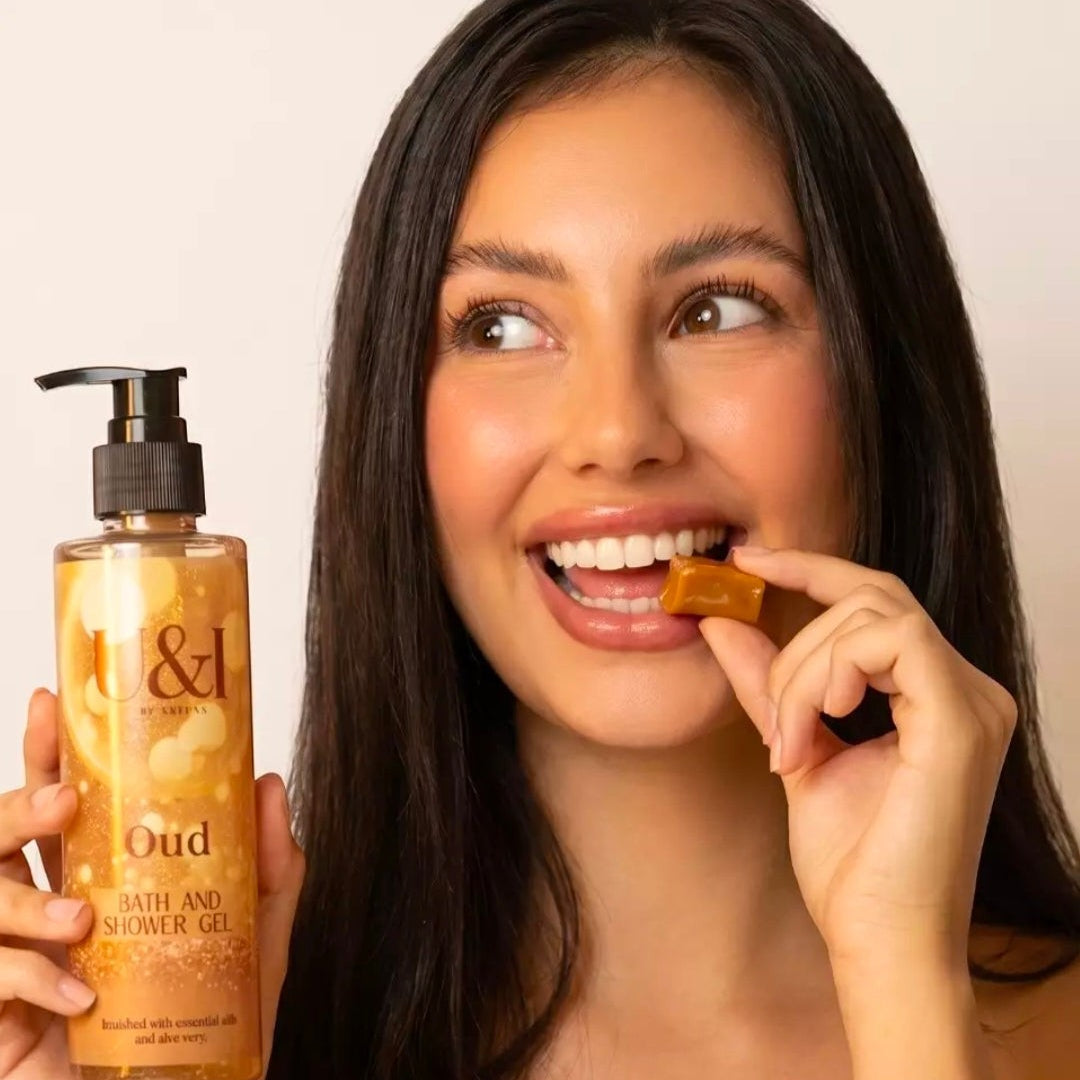 U&I Oud bath and shower gel in a 200ml pump bottle held by a smiling woman eating a caramel candy.
