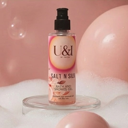 U&I Salt N Silk bath and shower gel bottle in a soft pink setting with bubbles and floral accents