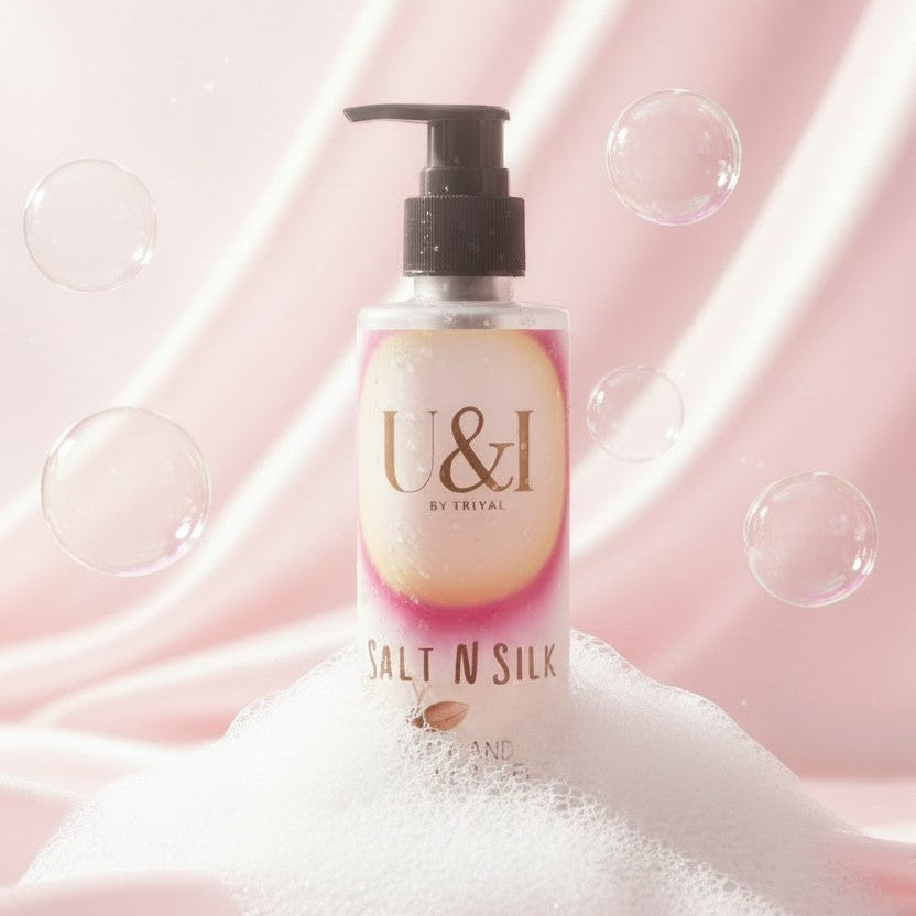 U&I Salt N Silk bath and shower gel bottle with a pump, surrounded by soap bubbles on a soft pink satin background.