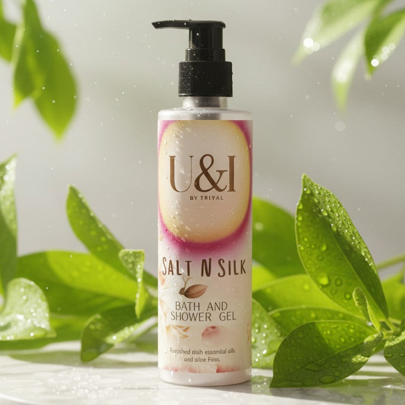 U&I Salt N Silk bath and shower gel bottle on a marble surface surrounded by fresh green leaves and water droplets.