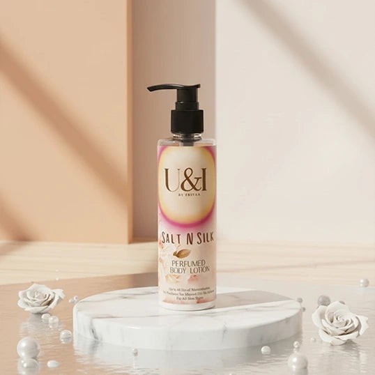 U&I Salt N Silk perfumed body lotion in a 200ml pump bottle on a marble pedestal with white roses and pearls.
