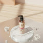 U&I Salt N Silk perfumed body lotion in a clear pump bottle on a marble pedestal with white roses and pearls.