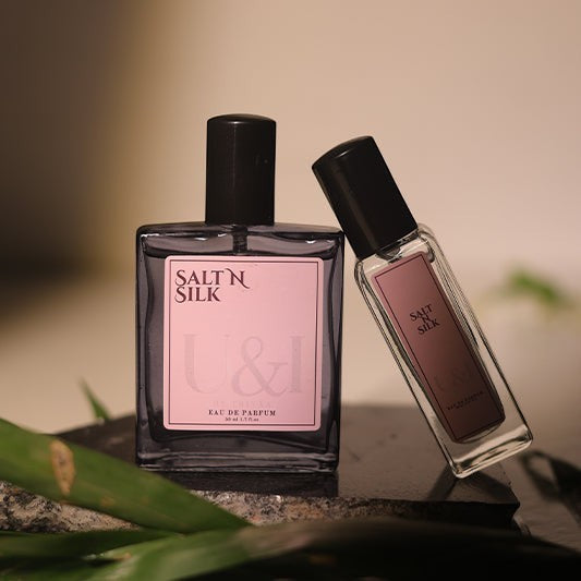 U&I Salt N Silk luxe fragrance perfume bottles with pink labels on a stone surface with green leaves.