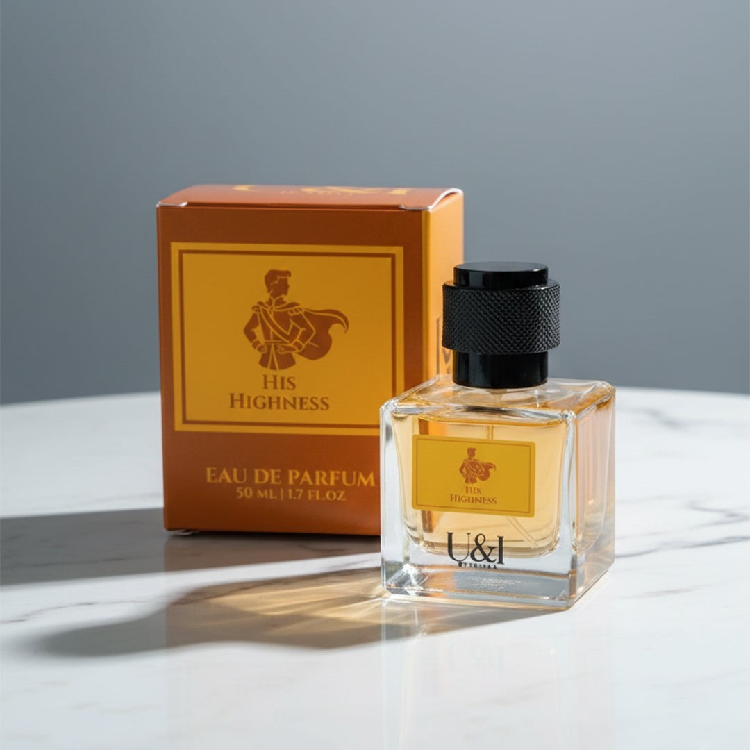 U&I His Highness eau de parfum in a glass bottle with a black cap next to its orange box on a marble surface.