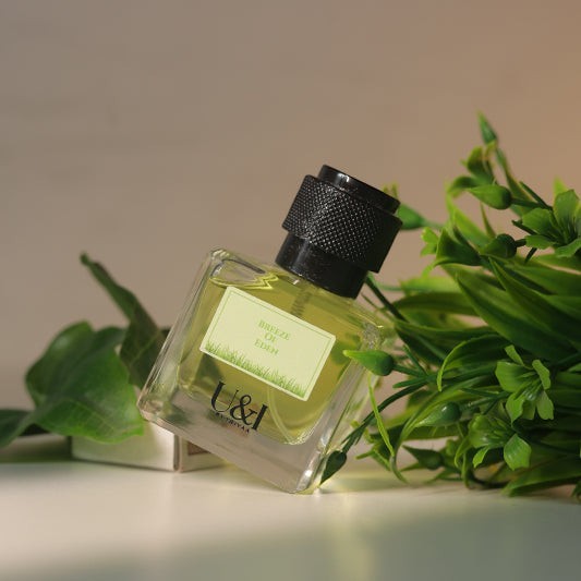 U&I Breeze of Eden perfume bottle with a black cap, surrounded by green leaves, evoking a fresh garden scent.