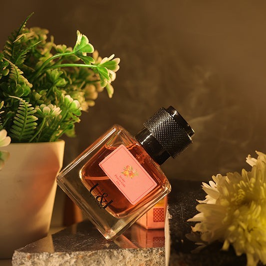 U&I In My Peach Girl Era perfume bottle with a peach-toned label, set against a warm, floral-accented background.
