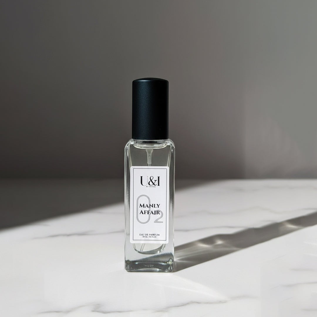 U&I Manly Affair eau de parfum in a clear glass rectangular bottle with a black cap on a white marble surface.